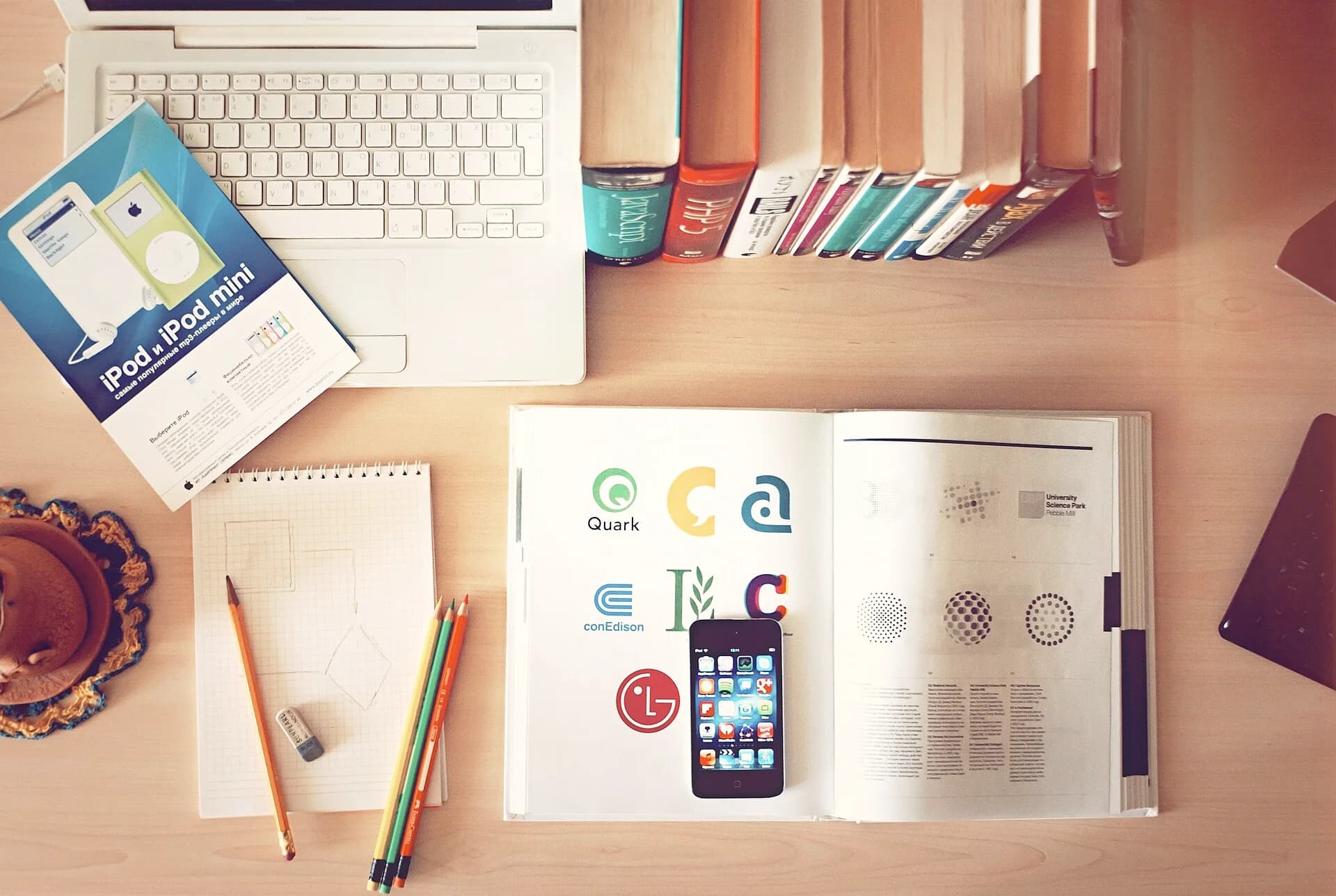 An open reference book, pencils and a keyboard on a study desk