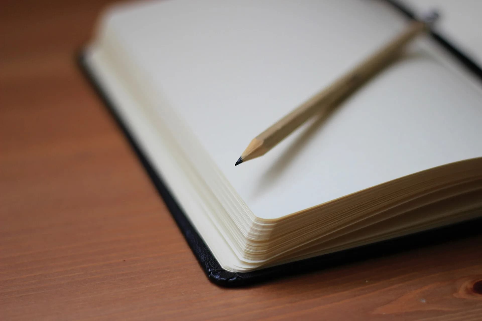 An open notebook and pencil on a wooden table