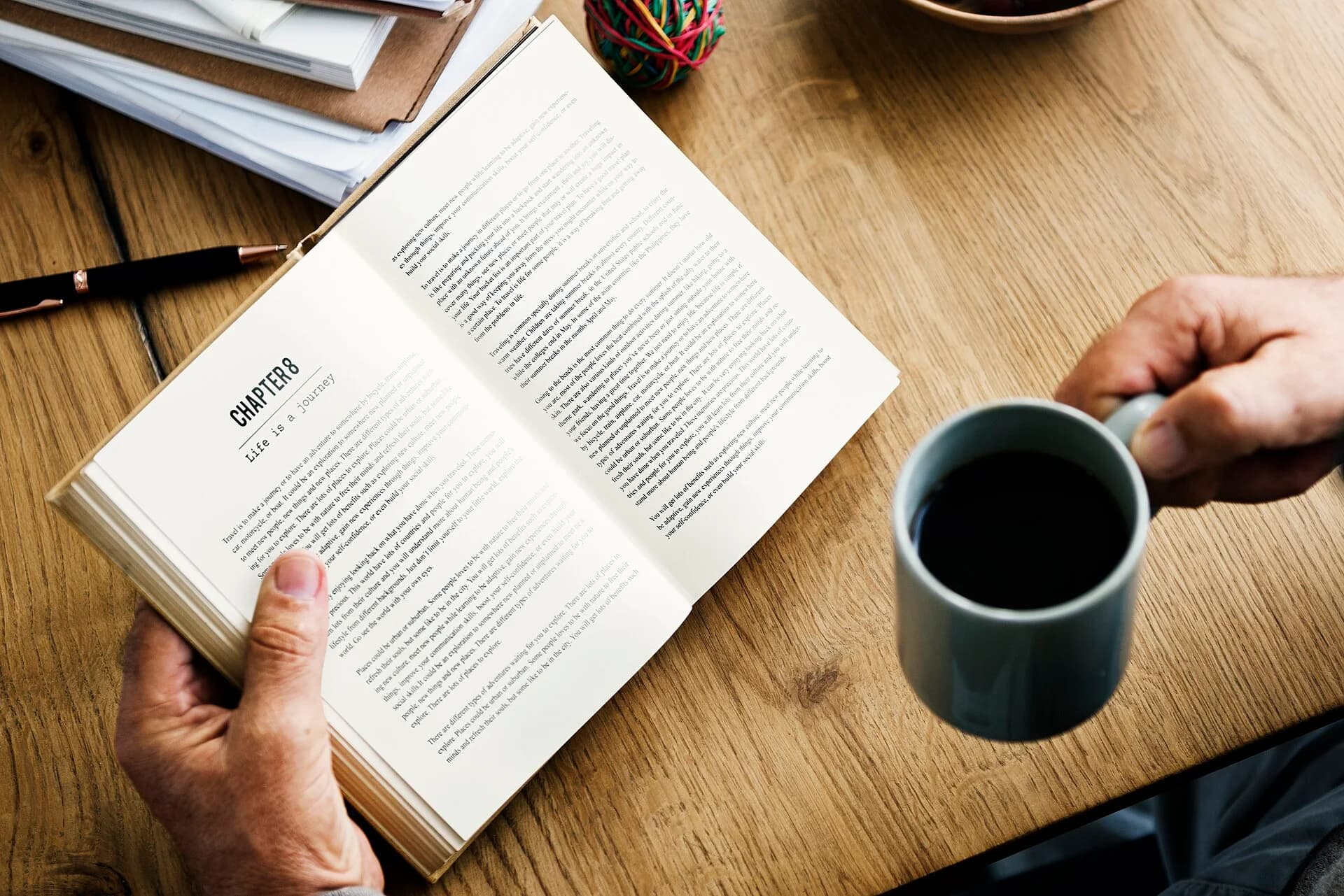 An open book on a wooden table with a cup of coffee