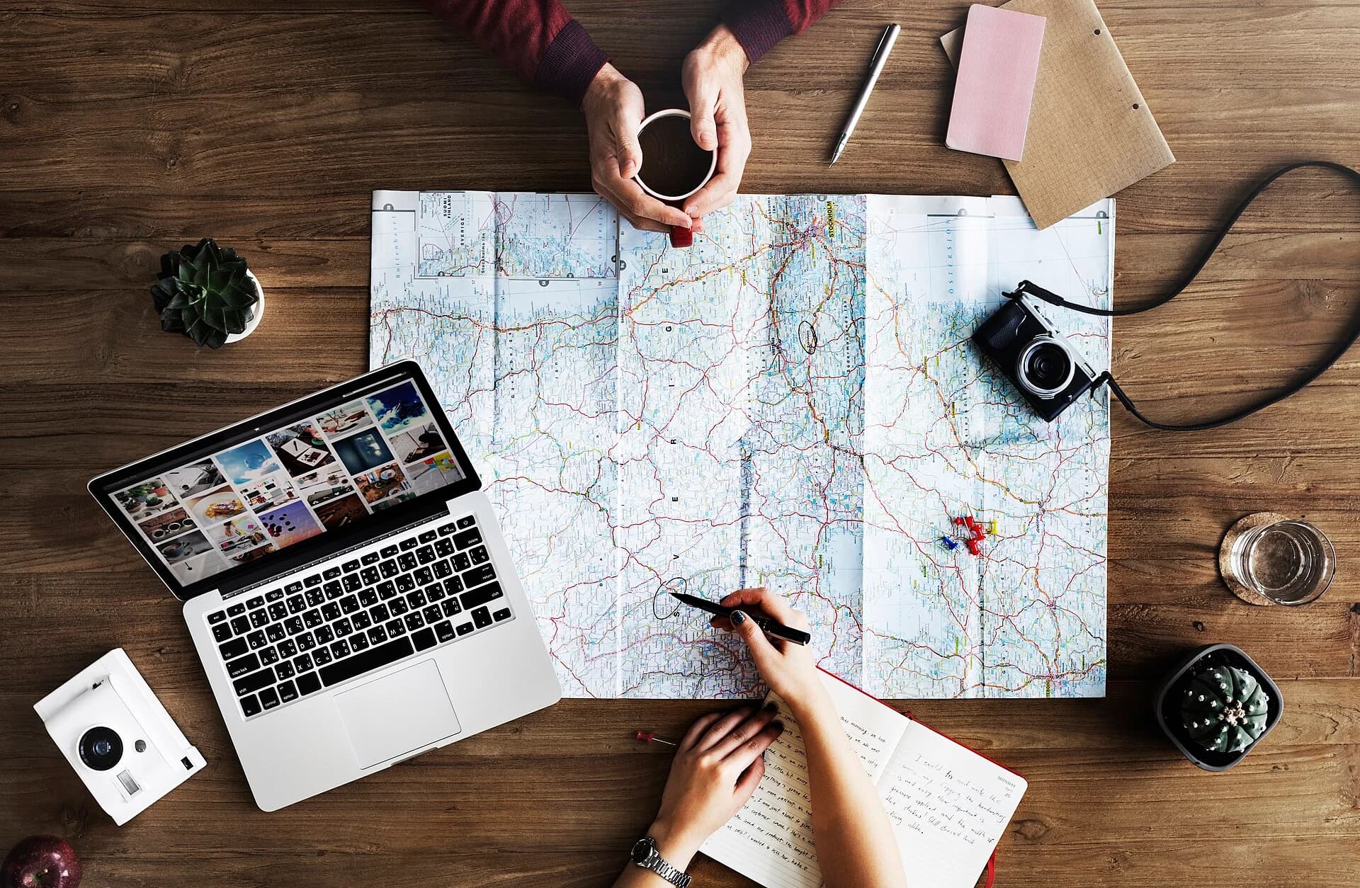 A map, notebook and camera on a table as a journey is planned